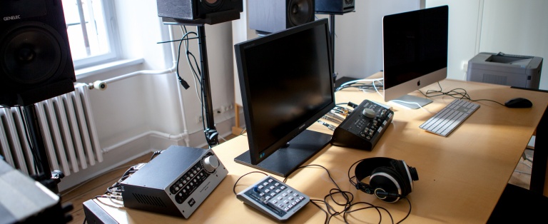 Computere og elektronisk udstyr på et bord. Højtalere bag bordet
