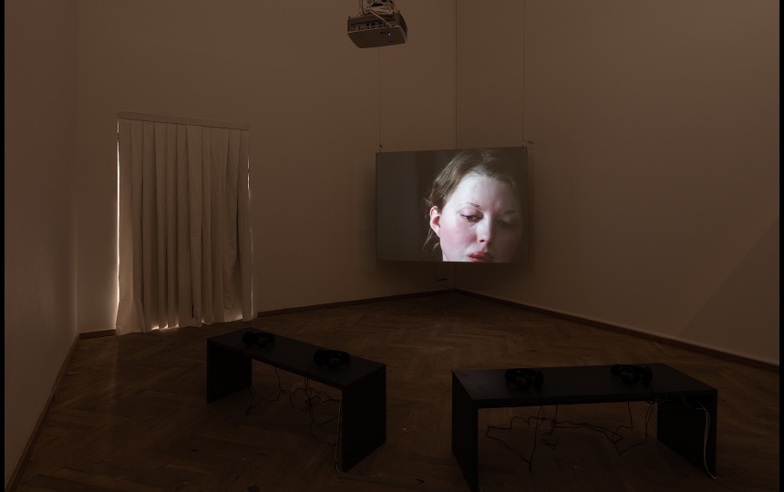 Installationsfoto af Luna Emilie Printz Scales' afgangsværk Eyelids (skærm med nøgen kvinde på plint som drejes af to personer)