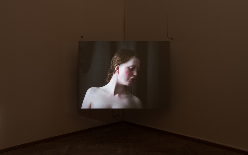 Installationsfoto af Luna Emilie Printz Scales' afgangsværk Eyelids (skærm med nøgen kvinde på plint som drejes af to personer)