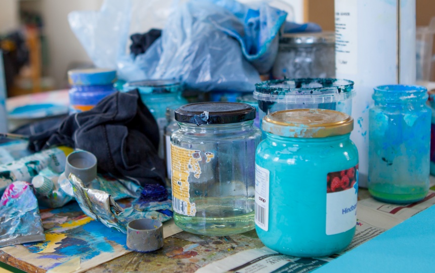 Malertuber, klude og syltetøjsglas med væske og maling