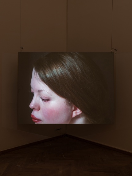 Installationsfoto af Luna Emilie Printz Scales' afgangsværk Eyelids (skærm med nøgen kvinde på plint som drejes af to personer)